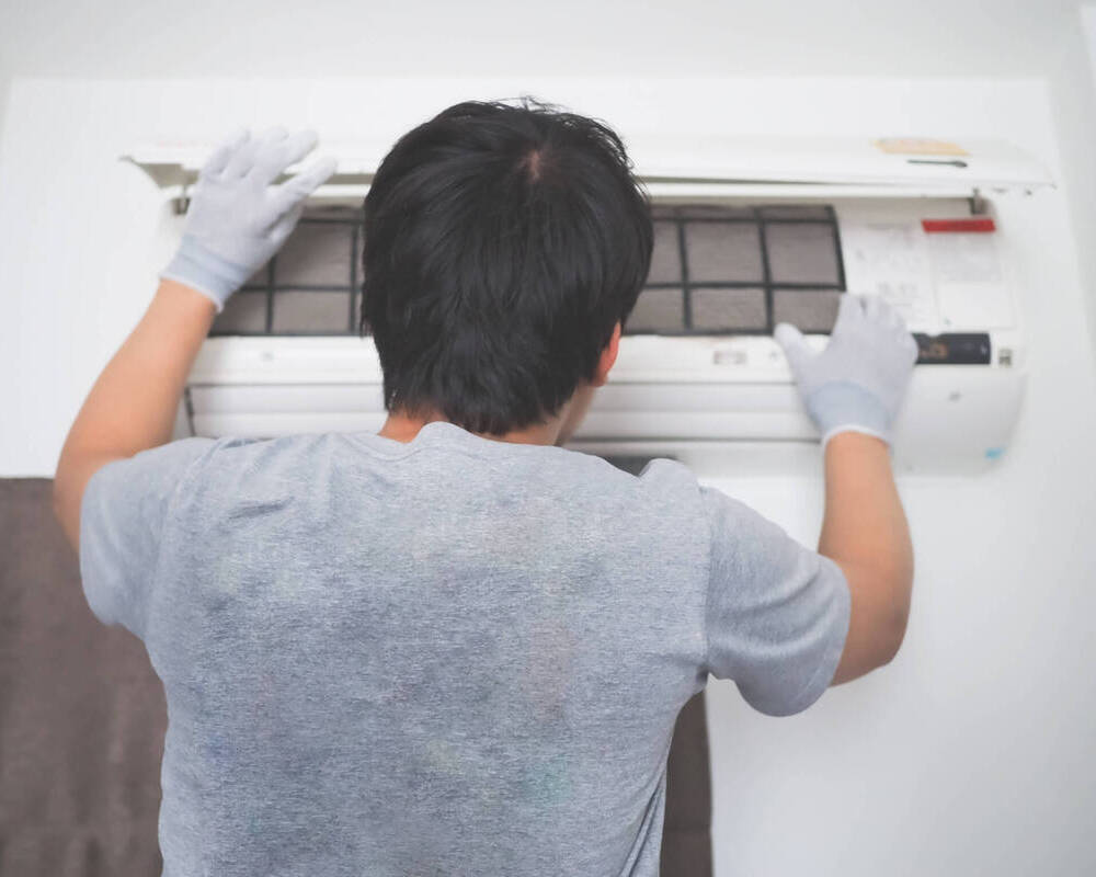 Men Cleaning The Filter Of Air Conditioner Interior Of The House